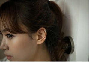 Detail view of a minimalist silver triangle ear cuff worn on the cartilage by a model