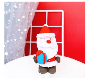 Close-up of Santa Claus cake topper figurine holding a blue gift box for Christmas decor