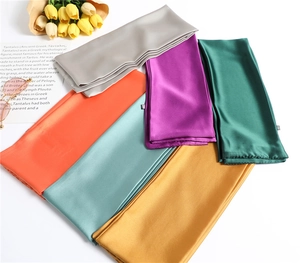 Flat lay of colorful narrow satin scarves with tulips and glasses on a white desk