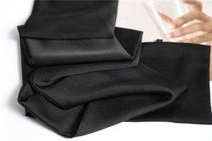 Macro shot of folded black satin fabric with silky texture and elegant sheen
