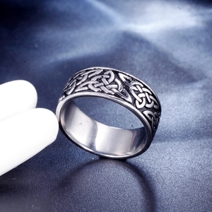Macro view of silver stainless steel ring with intricate Celtic knot patterns on blue fabric