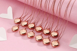 Twelve rose gold zodiac necklaces with name engravings on a soft pink textured backdrop