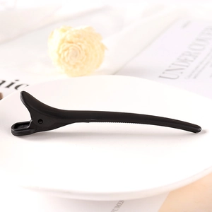 Detail of matte black claw clip on a white ceramic plate with soft aesthetic decor