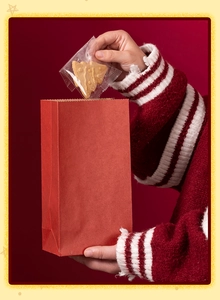 Dettaglio di un sacchetto regalo in carta kraft rossa con un biscotto natalizio