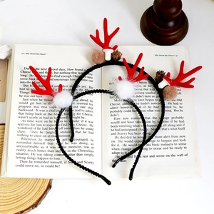 Christmas reindeer antler headband with white fur balls and pine cones on a book