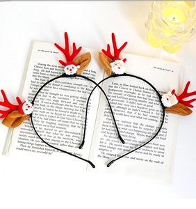 Detailed view of Christmas reindeer antler headband and Santa doll on vintage book pages