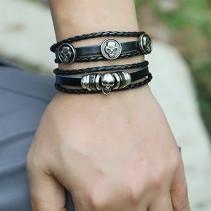 Close-up of a multi-layer black leather punk bracelet with metallic skulls on a wrist