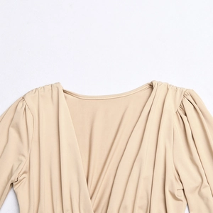 Detail showing beige deep V-neck bodysuit with pleated fabric and elegant drapery