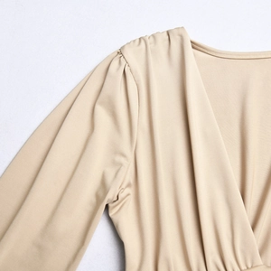 Detailed close-up of beige deep V-neck bodysuit with pleated shoulder and soft fabric texture