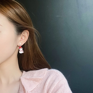 Close-up of a Christmas snowman earring with red scarf and gold star on model