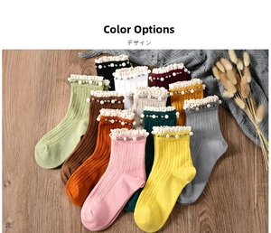 Flat lay of colorful cotton socks with ruffle edges and pearl bead details on wood