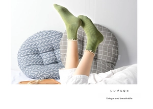 Detailed view of green ribbed cotton socks with elegant lace trim and pearl accents