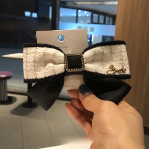 Détail de la pince à cheveux noeud en tweed avec pendentif Smile doré et chaîne