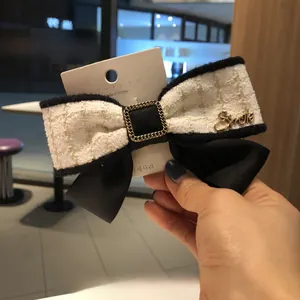 Détail de la pince à cheveux en tweed avec boucle dorée et lettrage Smile