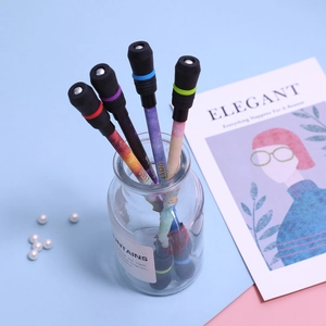 Detail view of colorful weighted spinning pens in a glass jar against a blue pink backdrop