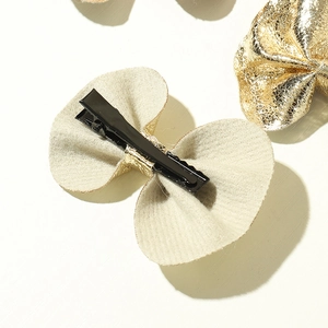 Detail of golden glitter bow hair clips featuring black metal alligator clip base for girls