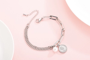 Detail of silver chain bracelet with Queen coin pendant and faux pearl accent