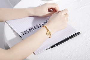 Detail of gold coin pendant and white pearl on double-layer chain bracelet for women