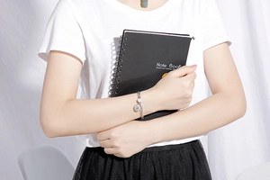 Detail of silver titanium steel chain bracelet with a coin pendant worn by a model