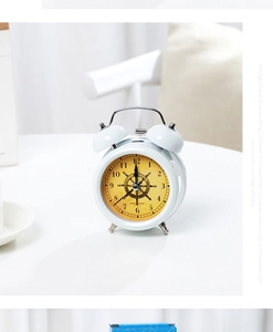 Close-up of a white vintage twin bell alarm clock with a golden navigation dial