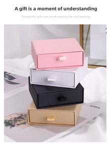 Vertical stack of drawer-style jewelry gift boxes in pink, white, black, and kraft paper