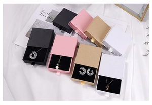 Detalle de cajas de joyería tipo cajón en negro rosa kraft y blanco con fondo de seda