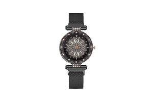 Detail of a rose gold watch face with floral rhinestone patterns and black mesh band