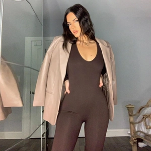 Close-up of a brown slim fit jumpsuit paired with a beige faux leather blazer jacket