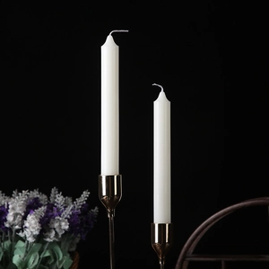 Classic white taper candles on gold metal holders against a black background