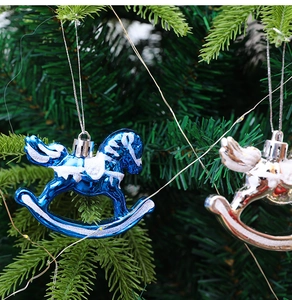 Close-up of blue and silver glitter rocking horse ornaments hanging on a Christmas tree