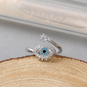 Vista macro de anillo ojo de la suerte plateado con circonitas y base de madera