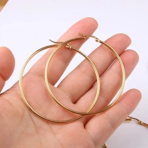 Klassische goldene Edelstahl-Creolen für Damen, zur Größenbestimmung in der Hand