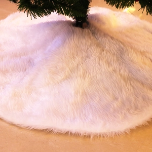 Plush white faux fur Christmas tree skirt showing a soft texture under warm holiday lighting