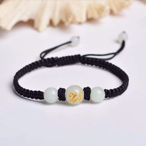 Detail of hand-woven black rope bracelet featuring a luminous bead with golden dragon motif