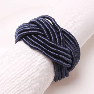 Close-up of deep blue braided rope napkin ring on a white rolled cloth napkin