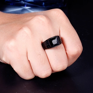 Close-up of men's black stainless steel ring with square black gemstone and grooved sides