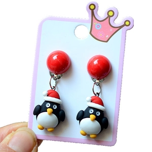 Detail of Christmas penguin clip-on earrings with red festive hats on white card