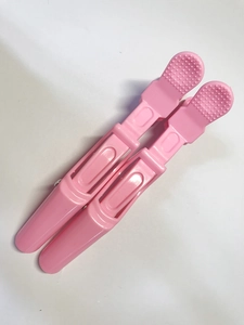 Close-up of pink plastic crocodile hair clips with non-slip handles for styling