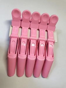 Detailed view of pink plastic sectioning hair clips for professional salon styling and dyeing
