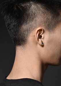 Gros plan d'une boucle d'oreille ronde noire minimaliste avec bord argenté sur un homme