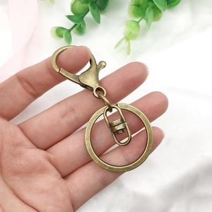 Detail of bronze metal lobster clasp keychain parts held by hand over white fabric