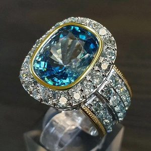 Luxury cushion cut blue gemstone ring with two-tone metal band and pavé halo setting