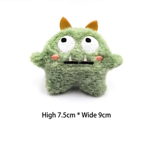 Detailed plush monster pin dimensions 7.5cm by 9cm with green fur and orange horns