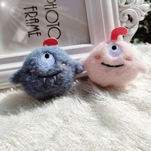 Close-up of cute plush monster brooches in grey and pink with fuzzy texture