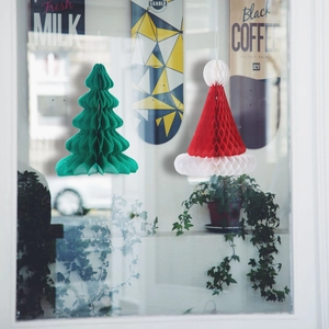 Green Christmas tree and red honeycomb paper ornaments hanging for festive holiday decor