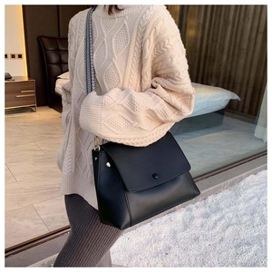 Close-up of black leather crossbody bag featuring geometric wide strap and gold hardware