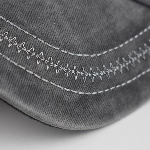 Macro shot of dark grey washed cotton brim with decorative cross-stitch and twin seams