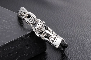 Close-up of vintage punk stainless steel totem charm on black braided leather bracelet