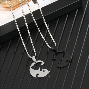 Detail of interlocking black and silver cat pendants on bead chains for couples