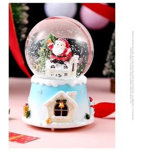 Close-up of a Christmas crystal ball music box with Santa Claus and festive resin base